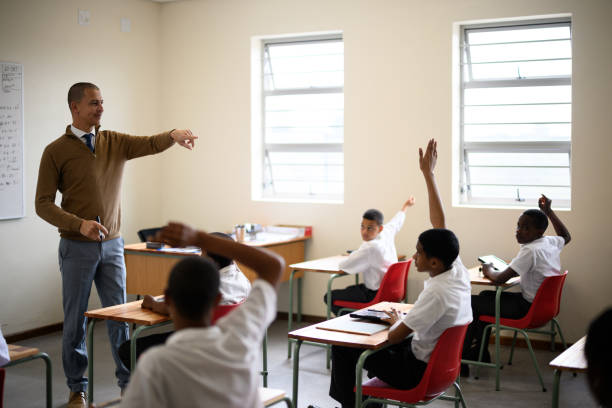 istock Teacher points as schoolchildren raise hands to answer question 1772380694