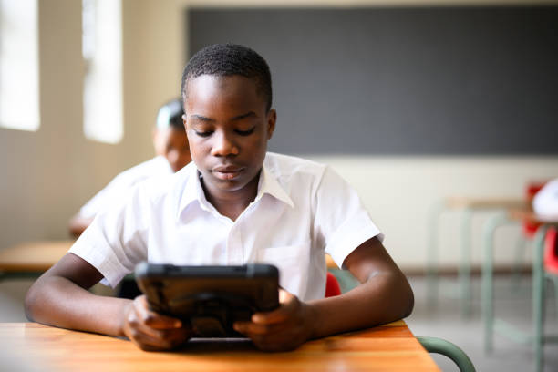 istock Young black schoolboy doing mathematics on digital table in classroom 1772380805