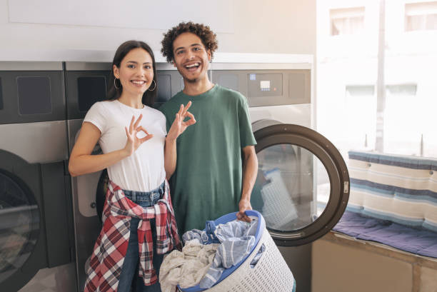 istock Couple Gesturing OK Posing Near Laundromat Washing Machines At Laundry 1772380896