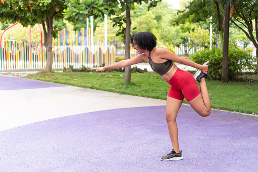 Afro-American female athlete stretching her legs after a hard workout.