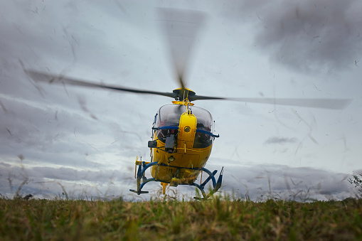 red rescue helicopter landing on airfield in valley in Bernese Oberland Switzerland.