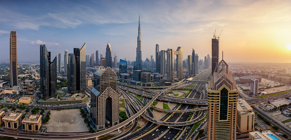 Panoramic sunset view of the modern skyline of Dubai, UAE, with skyscrapers reflecting the golden sunlight