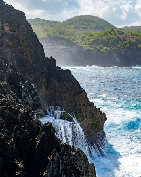 istock Powerful waterfall cascading off a rocky cliff into a tranquil blue sea 1772383795