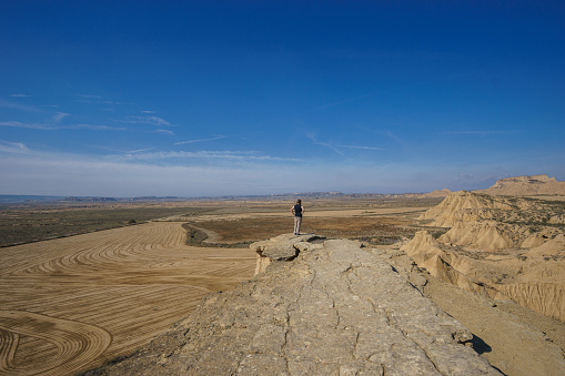 Hiker at Mirador de Juan Obispo looking at desert landscape of the arid plateau of the Bardenas Reales, Arguedas, Navarra, Spain