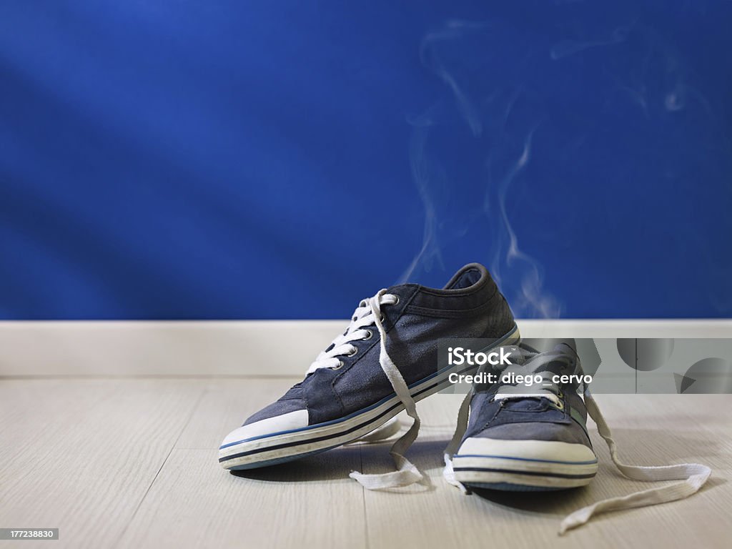 stinking worn-out shoes left on wooden floor concept shot of feet perspiration: bad smell coming out from old and dirty shoes Unpleasant Smell Stock Photo