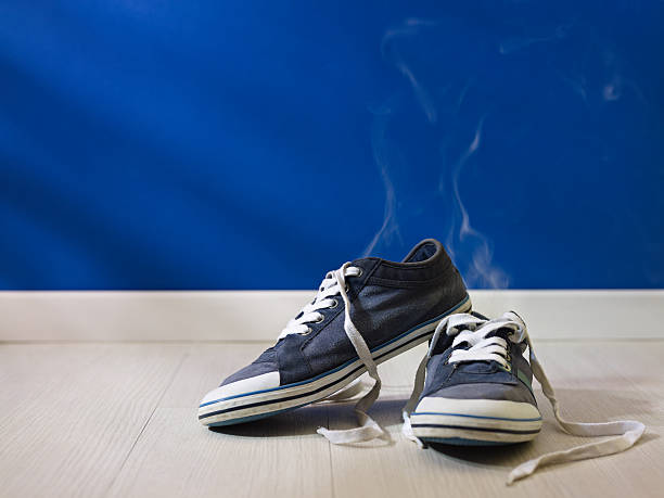 stinking worn-out shoes left on wooden floor stock photo
