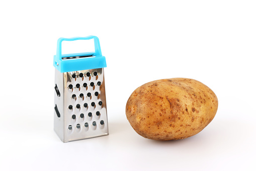 Hand made miniature grater and raw unpeeled potato on white background.