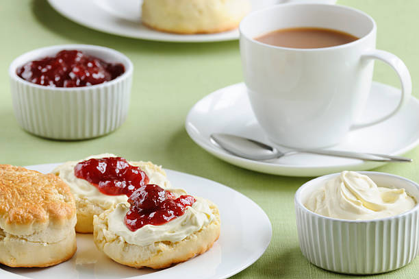 Cream tea with scones, cream and jam Traditional English cream tea of scones, clotted cream, strawberry jam and a cup of tea. These are served Devonshire style, with the jam on top. scone photos stock pictures, royalty-free photos & images