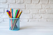 Colored pencils in pencil holder on wooden desks