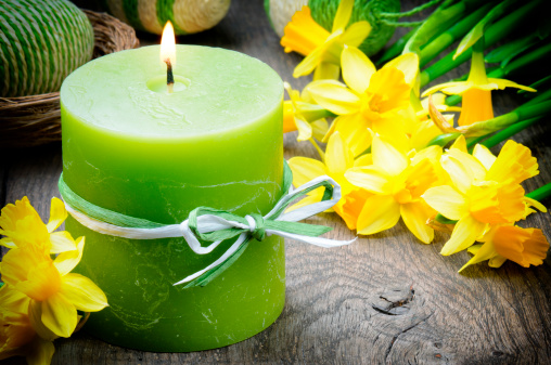 Spring setting with yellow narcissus and candle on the wooden table