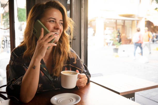 istock Happy young woman using mobile phone and enjoying coffee at cafe 1772404296