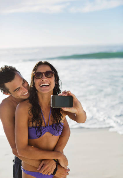 istock Happy couple taking self-portrait with camera phone on beach 177240922