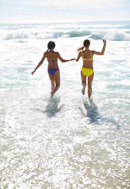 istock Friends in bikinis holding hands and running into ocean 177241055