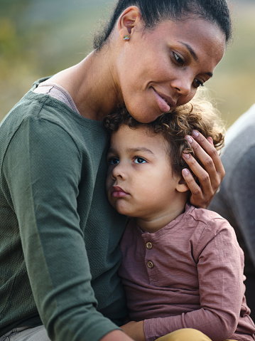 African American single mother consoling her sad son in nature.