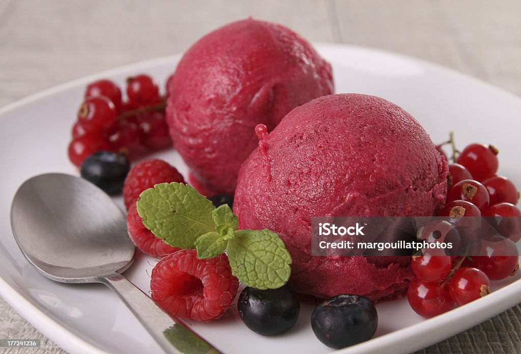 Sorbet on white plate with berries and spoon plate of ice cream and berries Sorbet Stock Photo