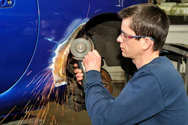 Man grinding a blue cars panel, focus on sparks. More car repair and painting photos in my portfolio.