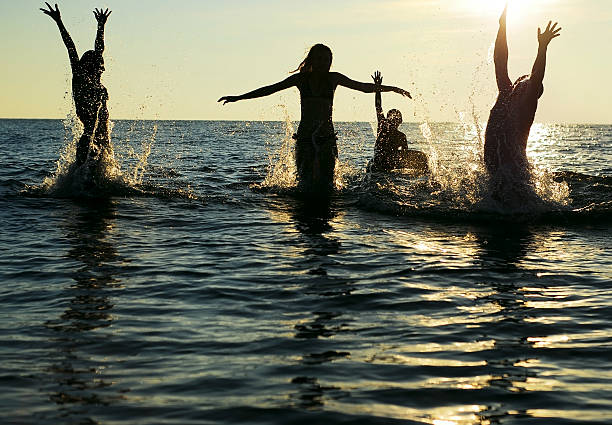 istock Silhouettes of several people jumping into ocean 177241312