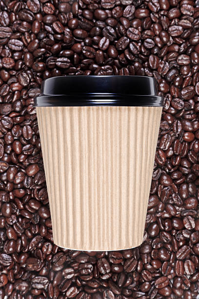 Takeaway disposable coffee cup Photo of a disposable recycled paper coffee cup with a mixture of arabica and robusta beans in the background. cup disposable cup paper insulation stock pictures, royalty-free photos & images