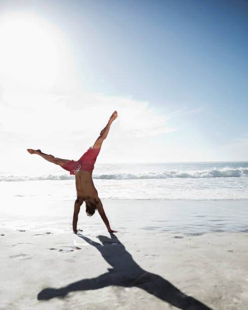 istock Man in swim trunks doing handstand on beach 177241497