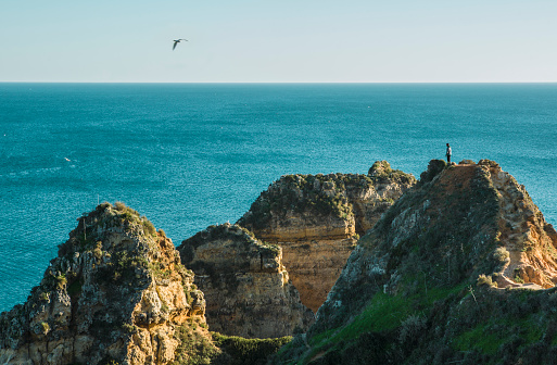 Tourist watching the sea from the top of a cliff of Ponta da Piedade, Lagos, Algarve region, Portugal