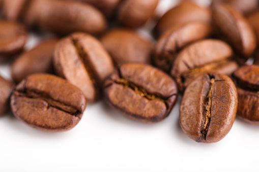 roasted coffee beans isolated in white background. Roasted coffee beans background close up. Coffee beans pile from top on white background with copy space for text. Good morning.