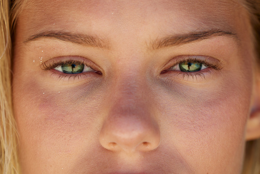 Extreme close up of green-eyed woman looking at camera.