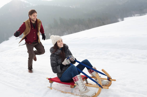 istock Happy couple sledding in snowy field 177242522