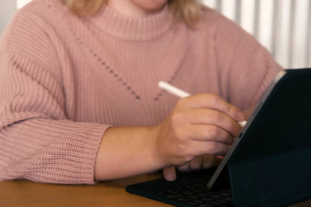istock Unrecognizable Woman hand using a graphic tablet computer with stylus pencil pen in a cafe. Cropped shot of female working on a digital touchscreen device in remote workplace. Corporate technology 1772431535