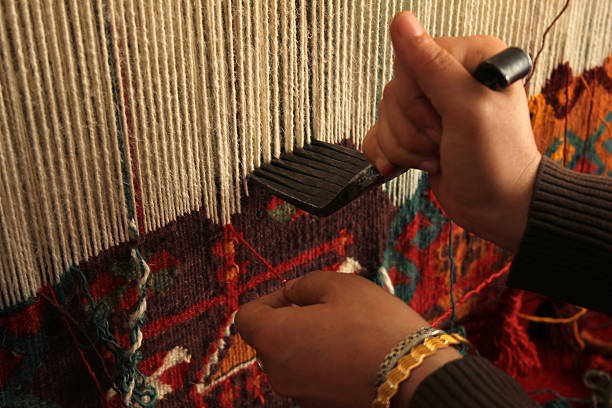 Close-up of a woman hand-weaving a colorful rug stock photo