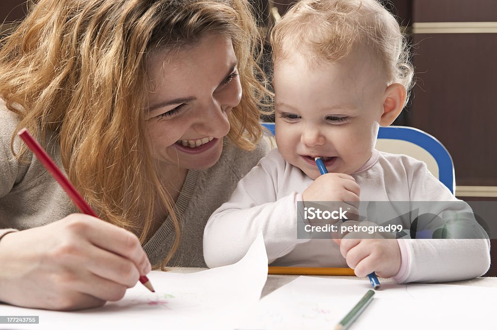Mother and daughter drawing Young mother and her baby daughter drawing with pencils 12-17 Months Stock Photo