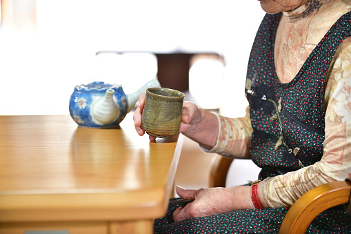 Japanese senior woman relaxing while drinking tea at the table in the living room