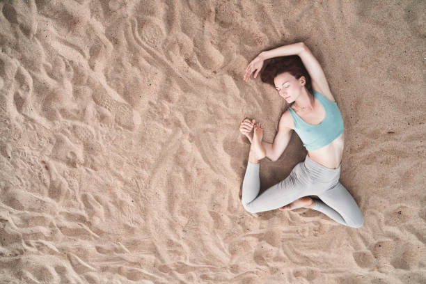 istock Top view of woman practicing yoga on sand beach. 1772444391