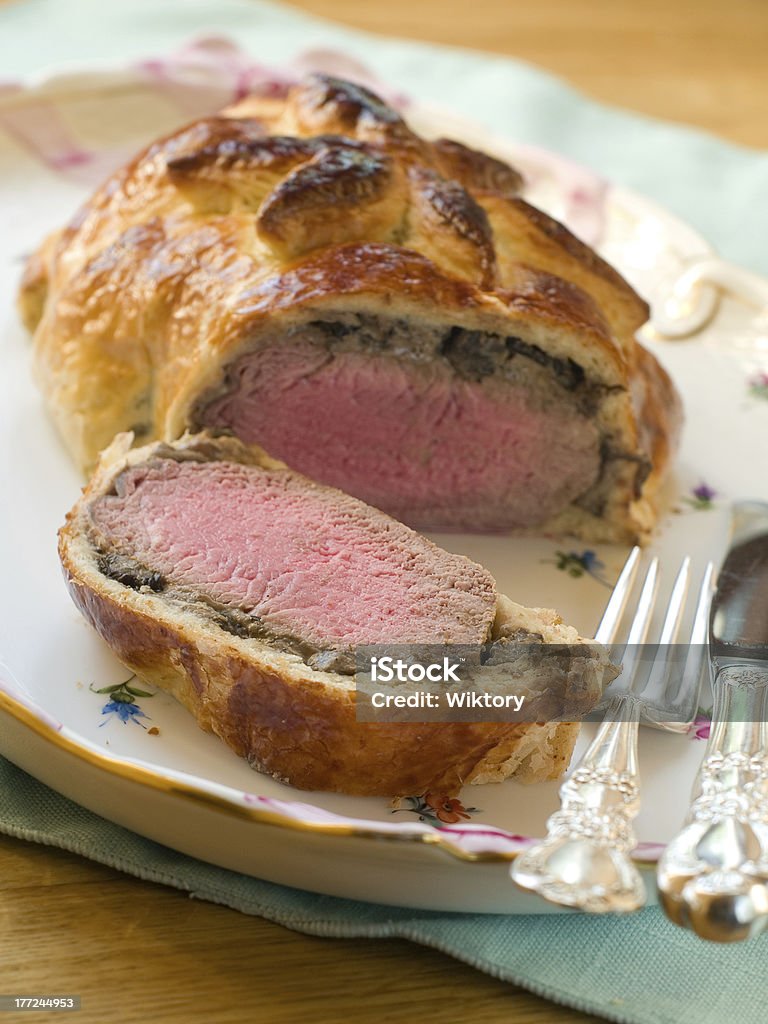 Beef Wellington "Slices of Beef Wellington on the serving dish witj knife and fork, selective focus" Beef Wellington Stock Photo