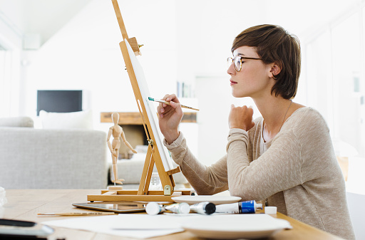 A beautiful woman sitting and drawing a watercolor at art studio.