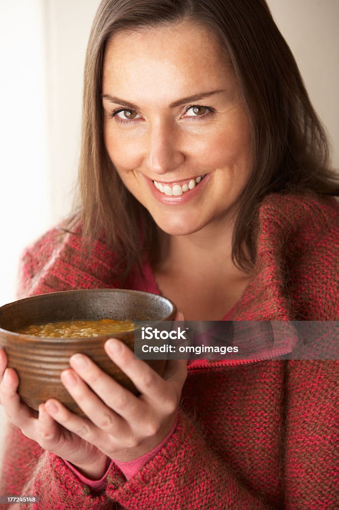 Woman holding a wooden bowl of soup and smiling Woman holding bowl of soup smiling at camera Soup Stock Photo