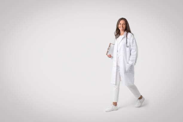 Cheerful senior woman doctor with stethoscope and medical chart walking over grey background, copy space, full length Cheerful senior woman in workwear doctor with stethoscope and medical chart walking over grey studio background, copy space for ad, full length. Healthcare, medical staff anamnesis stock pictures, royalty-free photos & images