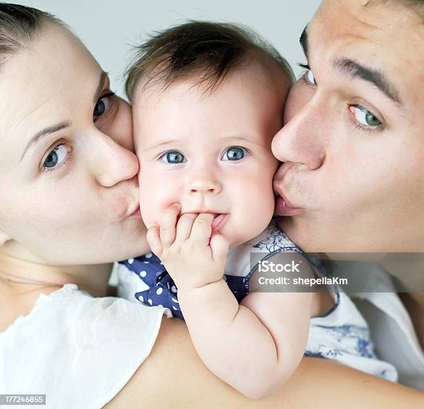 Mother And Father Kissing A Baby Between Them Stock Photo - Download Image Now - Adult, Baby - Human Age, Care