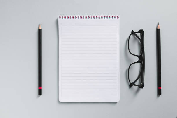 istock Top view of empty notebook, glasses and pen on grey office desk 1772477222