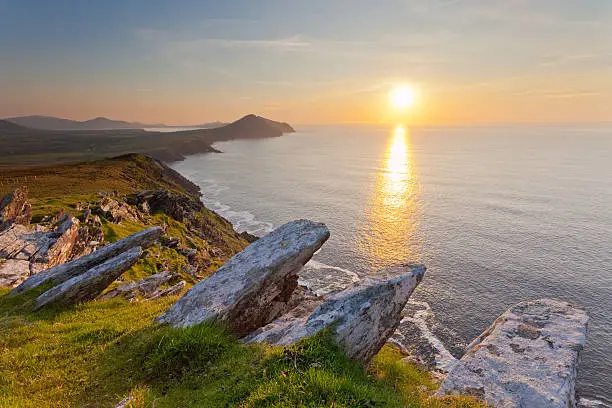ocean view from high cliffs overlooking dingle coastline with setting sun