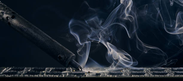 istock Backdrop of smoking soldering iron on dark background. 1772504296