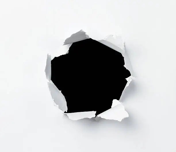 Hole in the paper sheet over black background