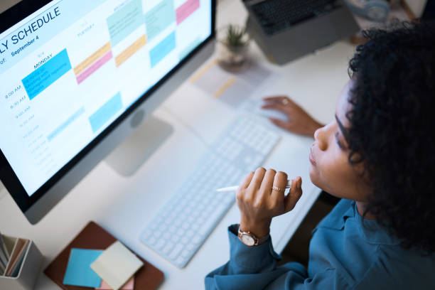 Woman with computer, thinking and checking schedule, agenda and reminder for office administration. Online calendar, planner and girl at desk planning spreadsheet for time management with high angle.