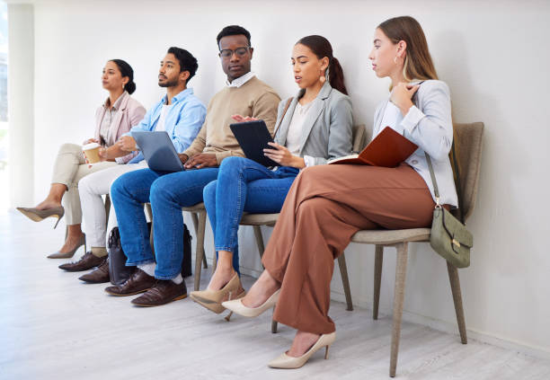 istock Business people, row and technology for interview, recruitment or hiring process in waiting room. Men, women and group together for career, onboarding or opportunity at company with diversity or web 1772522557