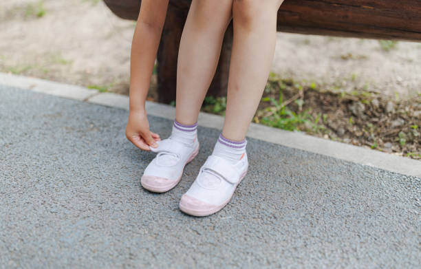 Girl puts on her shoes and learning to tie shoelaces in the hall