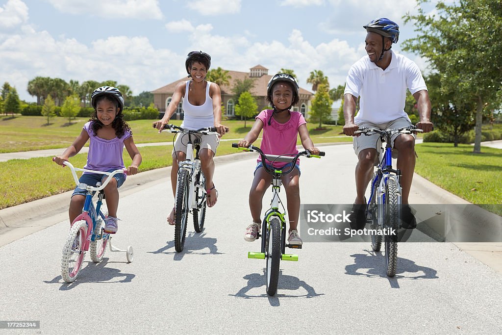 African American Family Parents and Children Cycling "A Black African American family of two parents and two children, two girls, cycling together." Family Stock Photo