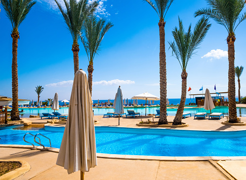 Sharm El Sheikh, Egypt - April 02, 2019: Beatiful clear swimming pool with palms at sunny place in hotel