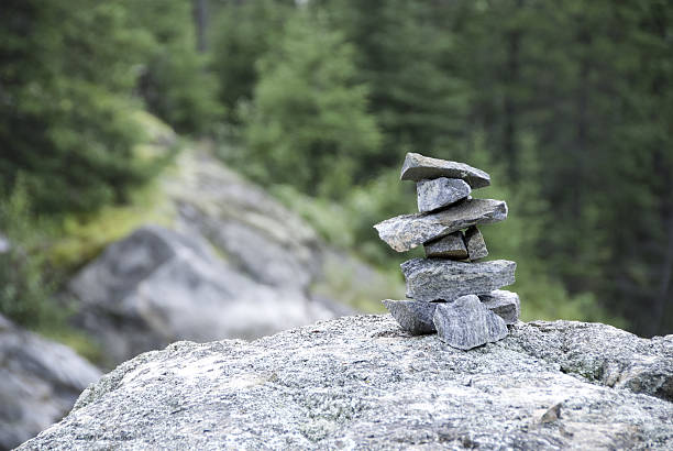 Inukshuk on Rock Ledge "A Inukshuk or Inunnguaq on a rock ledge at the side of the highway by Kenora Ontario.  It is used as a symbol to mark a person's having been there, or as a directional marking." kenora stock pictures, royalty-free photos & images