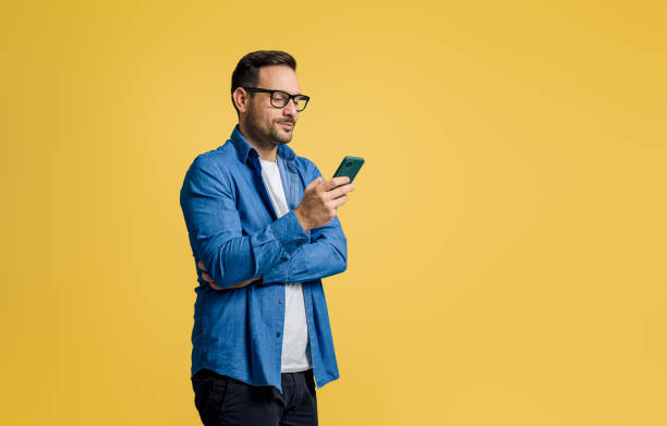 istock Confident handsome entrepreneur text messaging over mobile phone while standing on yellow background 1772537477