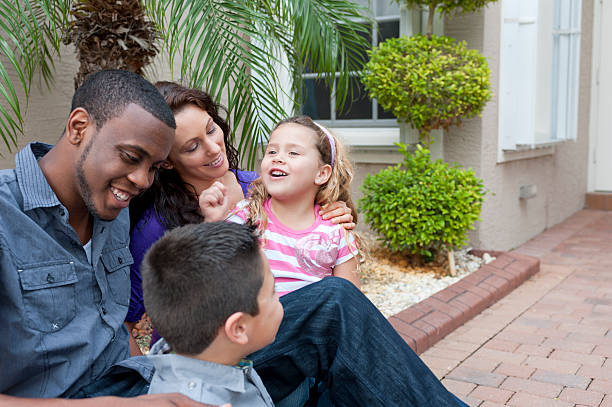 Multi ethnic family sitting in front of their house stock photo