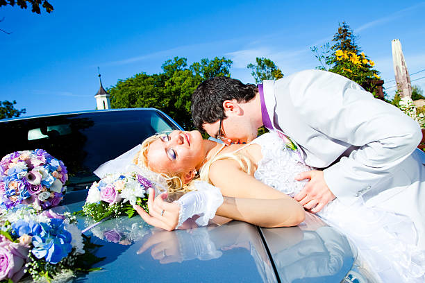 istock groom and bride kissing on a car cowl 177255253